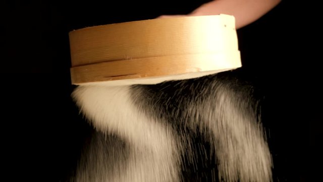 the girl holds a sieve in her hands and sifts flour