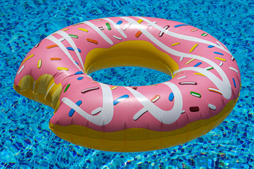 pink inflatable donut doughnut floating mattress in swimming pool. Beach pool accessories. Summer...