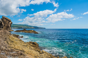 Fototapeta na wymiar Landscape with volcanic rocks from the islet of Vila Franca with mountains of the island of São Miguel in the background and Atlantic Ocean, Azores PORTUGAL