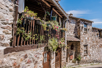 Fototapeta na wymiar Perspective of facades of typical schist houses with wooden balcony and several flowers in pots, Casal de São Simão PORTUGAL