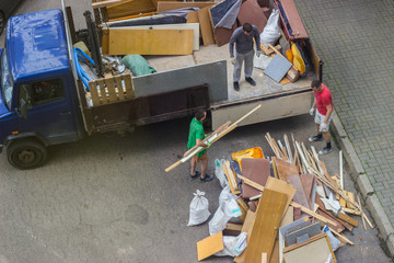 Workers load old furniture into the back of a truck to transport