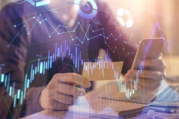 Double exposure of man's hands holding and using a phone and financial graph drawing. Analysis concept.