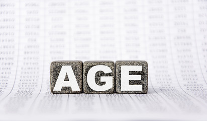 three stone cubes on the background of white financial statements, tables with the word age. Strong business concept