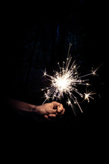 hand with sparkler on black background 