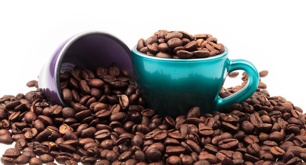 Cups of coffee with beans in and spilled around isolated on white