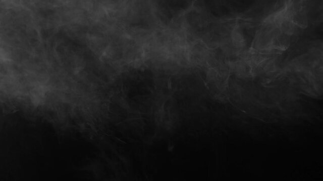 Spooky magic halloween. Atmospheric smoke VFX element. Abstract smoke cloud.  White smoke slowly floating through space against black bg