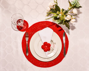 Red handmade crochet sousplat, white plate, white dessert plate and red crochet flower.