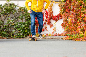 Male person doing skateboard trick stunts during autumn