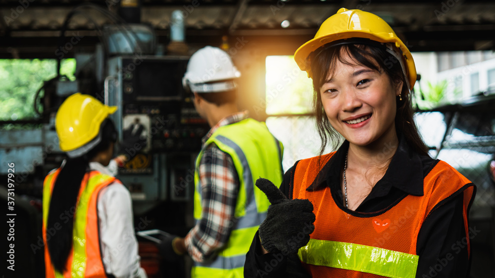 Wall mural portrait of worker show thumb up in industry with team working background in factory