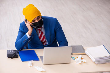 Sick male employee suffering at workplace from coronavirus