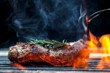 Grilled steak meat on the grill of the grill that has a flame