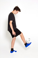 A young boy in a black sports t-shirt and shorts, training and playing with a soccer ball.
