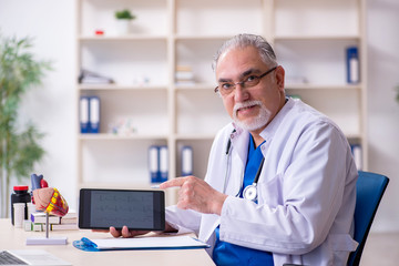 Old male doctor cardiologist in telehealth concept