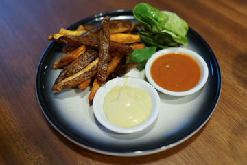 Fried potato with mayo and chili dip served on a plate
