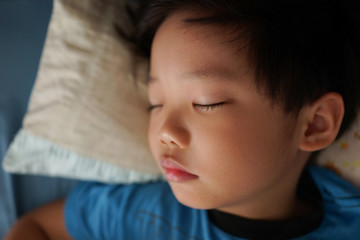 Obraz premium Portrait of a tired little Asian boy sleeping on his bed.