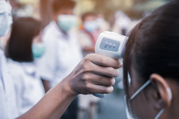 Hand holding Infrared thermometer gun forehead temperature test to check student for protect virus covid-19 symptoms in the school