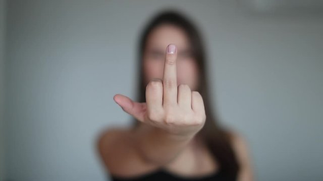 Young woman showing middle finger to camera. Defiant Girl provocative gesture