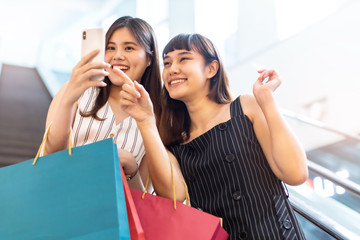 Happy asian woman with shopping bags enjoying in shopping.lifestyle concept.Smiling girl  holding colour paper bag.Friends walking in shopping mall.time shopping .