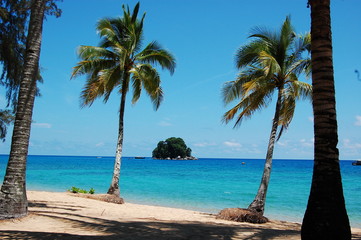 Fototapeta na wymiar 東南アジアのマレーシアにあるトロピカルリゾートのティオマン島のビーチにあるヤシの木と向こうに見える青い海と小島