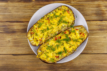 Baked stuffed eggplants on a wooden table. Top view. Healthy food and dieting concept