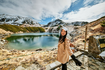 Asian woman is standing at swamp that is named Mikurigaike in Tateyama-Kurobe alpine route or Japan Alps in Toyama, Japan