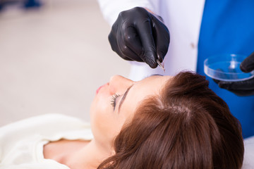 Young woman visiting male beautician in hair transplantation con