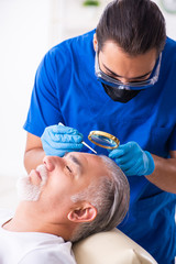Old man visiting young male doctor in hair transplantation conce