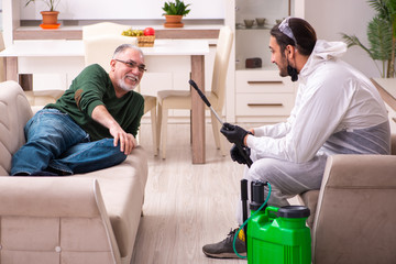 Young male sanitizer and old man indoors