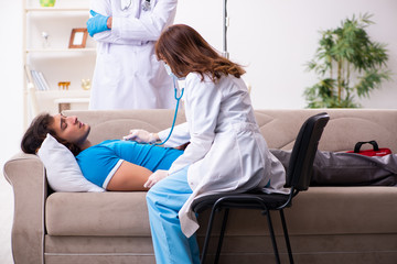 Obraz premium Two doctors visiting sick young man at home