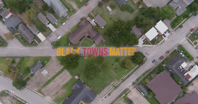 Bird eye view of a large "Black Towns Matter" sign painted on street in Houston Historical independence Heights district. This video was filmed in 6k and down scaled to 4k for best image quality.