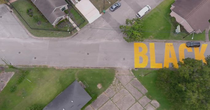 Bird eye view of a large "Black Towns Matter" sign painted on street in Houston Historical independence Heights district. This video was filmed in 6k and down scaled to 4k for best image quality.