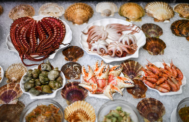 Fish shop market counter with seafood. Shrimps, octopuses, sea snails on ice