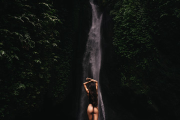 young woman backpacker looking at the waterfall in jungles. Ecotourism concept image travel girl