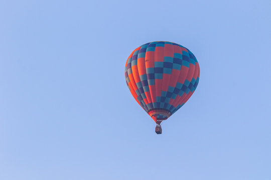Hot air balloon in flight against a background of blue sky. Colorful balloon watercolor painting.