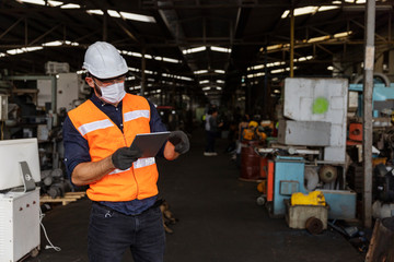 Factory in new normal. Male mechanical engineer with safety jacket and face mask checking warehouse or store