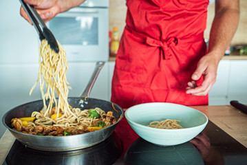 chef cooking noodle with vegetables and chicken