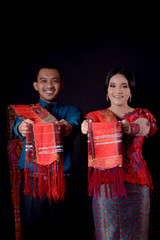 portrait of beautiful indonesian couple wearing traditional batak costume isolated on black background.