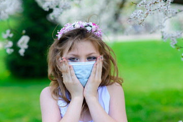 Teenager girl in medical mask in spring flowering garden. Concept of social distance and prevention of coronavirus.