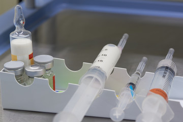 A syringe with white anesthetic drug and medications on  the table