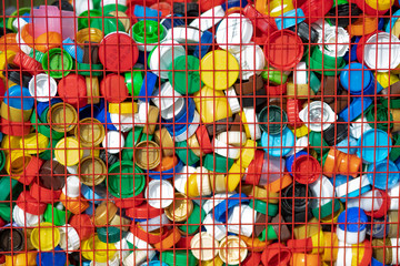 Texture of multi-colored plastic lids in a box of red rods. Recycling of recyclable materials.

