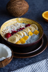Oatmeal with chia seed, bananas and oranges served in a bowl