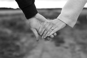 A loving young couple holding hands. Hands of a girl and a guy close-up. On a date boy and girl on the nature