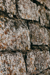 An old medieval stone wall, grass and moss on it. Wallpaper, natural background, copy space, soft focus.