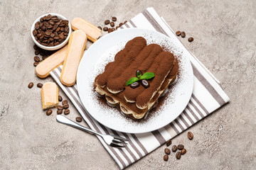 Classic tiramisu dessert and savoiardi cookies on ceramic plate on concrete background