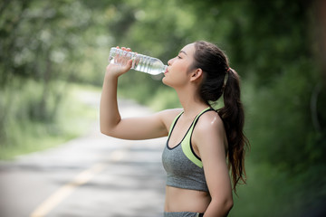 Young women rest  to drink water after exercise.