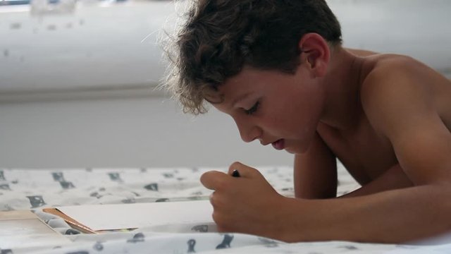 Child doing homework in front of laptop. Young boy studies at home doing online class