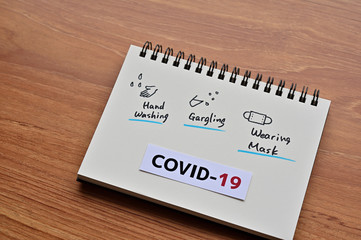 There is a notebook with illustration "Gargle, hand washing and mask" as  coronavirus infection control.