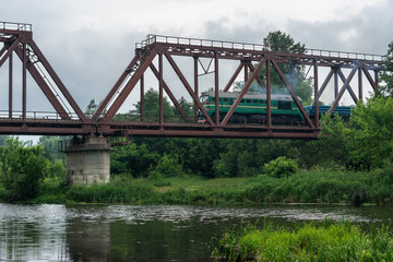 Freight train rides on a railway bridge over the river