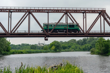 Freight train rides on a railway bridge over the river