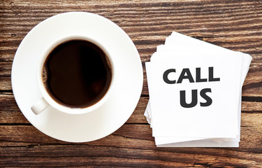 Business CALL US . White stickers with text on the wooden background with coffee